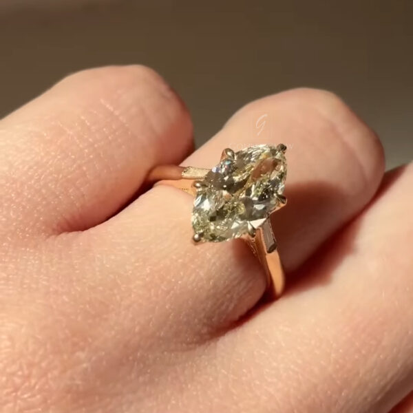 Pear shaped yellow diamond engagement ring shown on a hand, featuring a light yellow pear cut diamond set in a slim yellow gold band. The stone is held with elegant prongs and sparkles in natural light, highlighting its elongated shape and refined solitaire design.