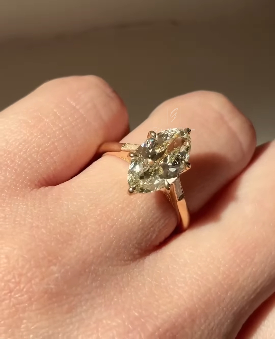 Pear shaped yellow diamond engagement ring shown on a hand, featuring a light yellow pear cut diamond set in a slim yellow gold band. The stone is held with elegant prongs and sparkles in natural light, highlighting its elongated shape and refined solitaire design.