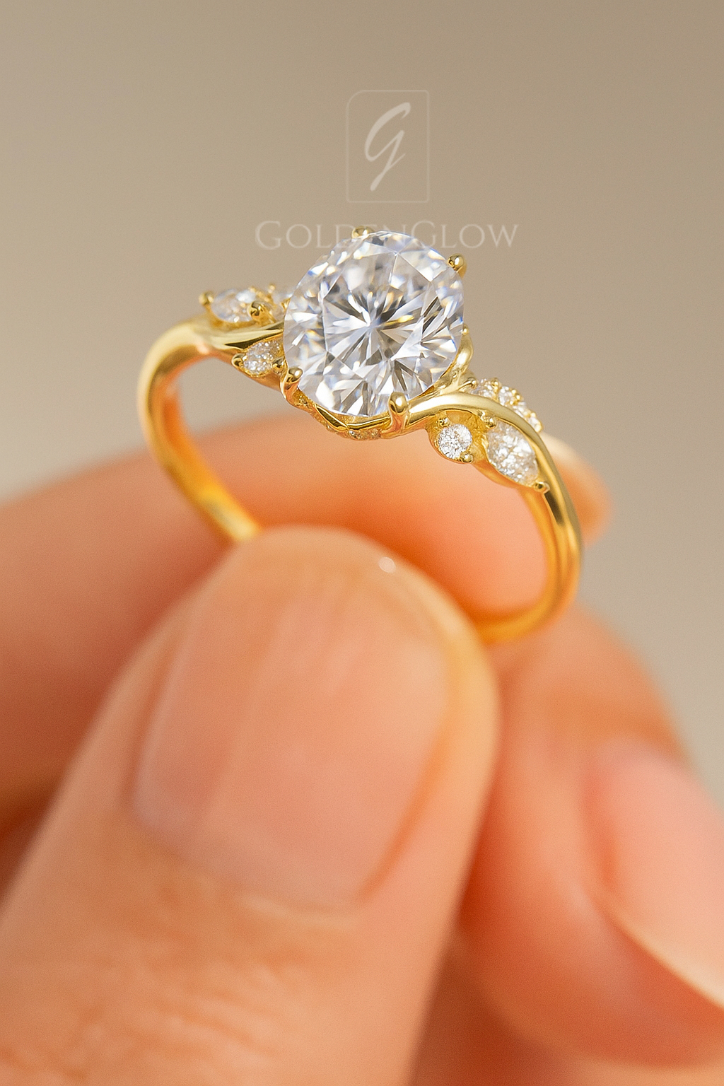 Close-up side view of a yellow gold engagement ring held between fingers, featuring a round brilliant center stone secured in claw prongs. The sculpted band curves gracefully and is accented with small pavé diamonds along the shoulders, highlighting the elegant setting and refined craftsmanship against a soft neutral background.