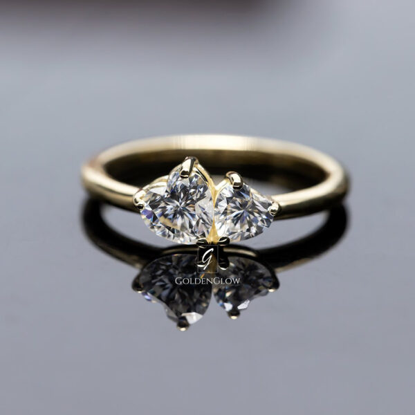 Toi et moi diamond ring featuring two brilliant-cut diamonds set side by side on a polished yellow gold band. The asymmetrical twin stone design symbolizes connection and balance, with refined prong settings highlighting sparkle and clarity. Elegant minimalist engagement ring photographed on a clean reflective surface, emphasizing modern luxury and craftsmanship.