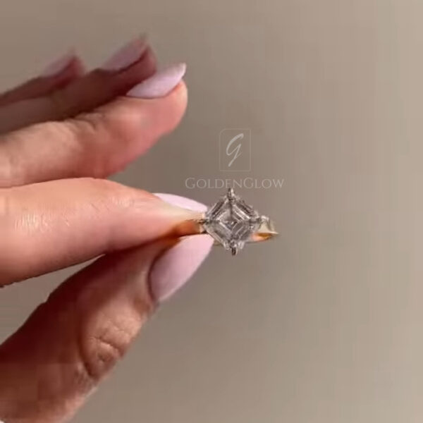 A direct top-down shot emphasizing the mesmerizing geometry of the Asscher-cut lab grown diamond or Moissanite. The concentric square facets create a hypnotic "windmill" pattern, characteristic of high-quality step cuts. The yellow gold prongs are visible at the corners, protecting the stone while adding a touch of warmth. This perspective highlights the stone's symmetry and clarity, showing off the clean lines and lack of inclusions that make lab-created stones a superior choice for step-cut lovers.