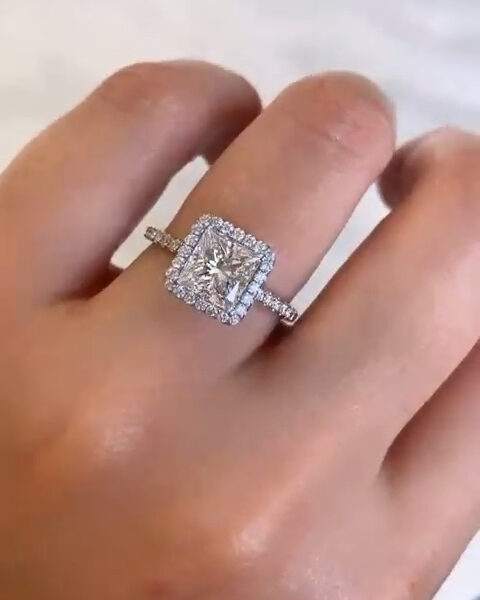 Detailed front view of a princess-cut halo engagement ring showing exceptional brilliance and symmetry. The center stone is framed by a delicate halo of small round diamonds, enhancing size and sparkle, while the thin pavé band adds refined elegance. This image highlights the fire and clarity of a lab grown diamond or moissanite diamond, making it ideal for a classic yet eye-catching engagement ring style.