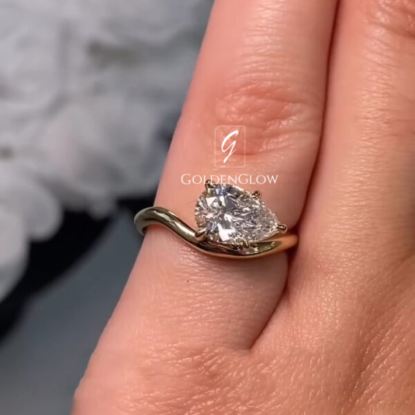 A sharp profile view focusing on the bridge and gallery. The hidden halo of tiny diamonds adds a glittery underline to the main stone. The scroll engraving on the yellow gold shank is crisp and detailed. The center lab grown diamond or Moissanite is crystal clear, showing deep contrast. This view proves that lab-created stones offer the same visual perfection and luxury as mined equivalents, set in a bespoke mounting.