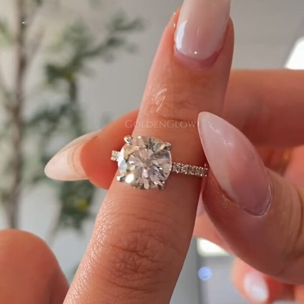 A breathtaking top-down close-up of the ring, focusing entirely on the brilliance of the oval center stone and its surrounding halo. The lab grown diamond or Moissanite features a "crushed ice" facet pattern, reflecting light in a dazzling array of sparkles. The seamless halo of smaller diamonds increases the visual footprint of the ring, making the center gem appear massive. This shot emphasizes the colorless quality of the stone and the perfect symmetry of the oval shape, ideal for a statement engagement piece.