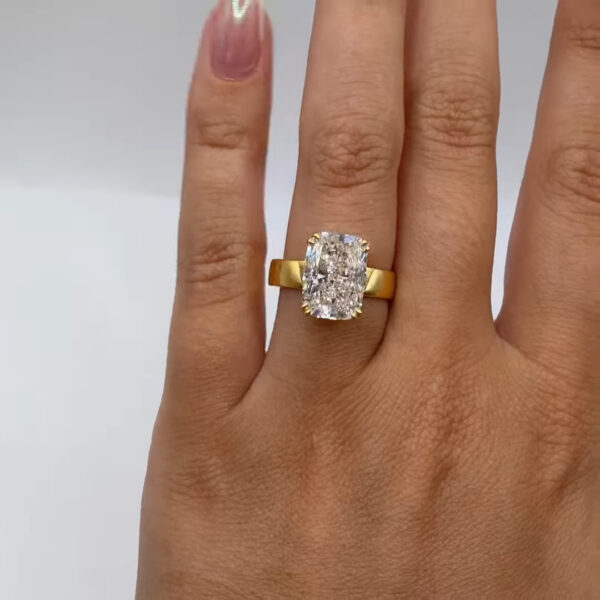 Hand modeling a oval diamond solitaire ring in yellow gold, captured from a straight-on angle. The elongated center stone reflects bright flashes of light, while the smooth gold band delivers a sleek, minimalist aesthetic perfect for a modern engagement ring.