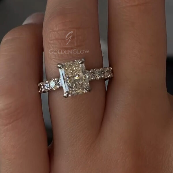A detailed lateral view focusing on the height of the setting. The radiant-cut center stone sits proud of the finger, supported by a sturdy yellow gold basket. You can see the depth of the pavilion and the thickness of the girdle. The band remains a consistent width, offering a comfortable fit. This shot allows potential buyers to visualize how the ring would pair with a wedding band and appreciate the substantial gold weight used in its construction.